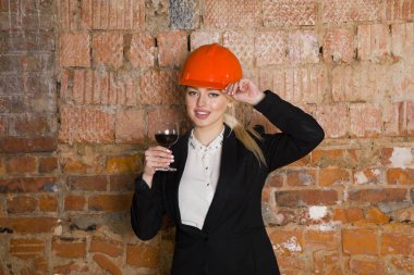 Mimar öğrenci veya ressam kadeh şarap ile portresi ve miğfer korumak. Tuğla kırmızı arka plan.