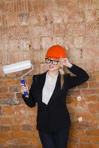 Mimar öğrenci veya rulo ile ressam portre ve miğfer korumak. Tuğla kırmızı arka plan.