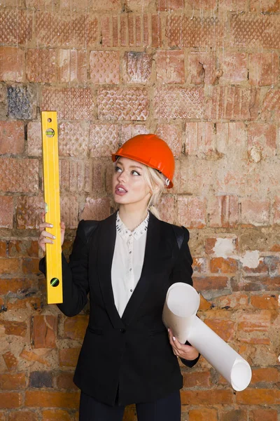 Mimar öğrenci veya planları ile ressam portre korumak kask giyiyor. Tuğla kırmızı arka plan.