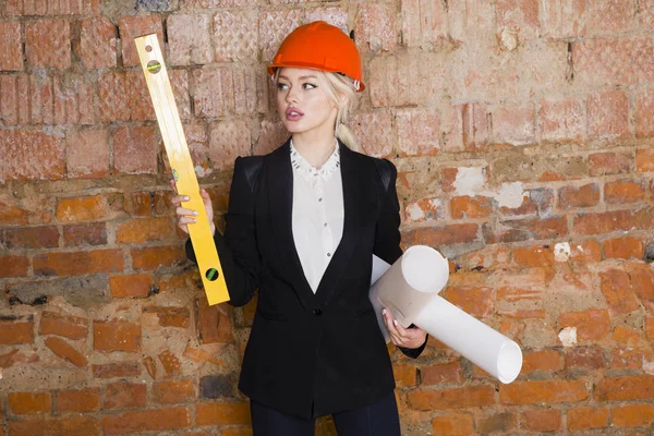 Mimar öğrenci veya planları ile ressam portre korumak kask giyiyor. Tuğla kırmızı arka plan.