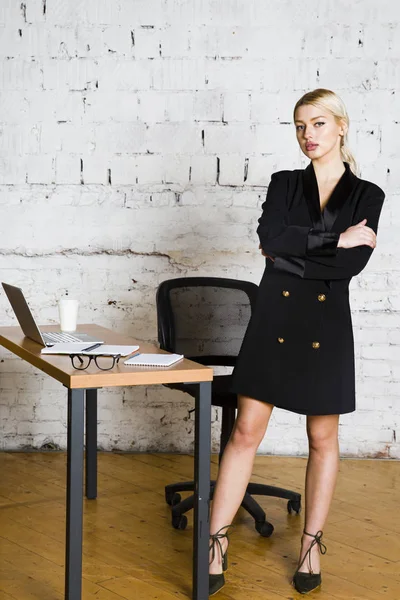 Genç sarışın güzel işkadını dizüstü bilgisayar, dizüstü bilgisayar ve gözlük kıyafetli bir office masada oturuyor. İş kavramı.