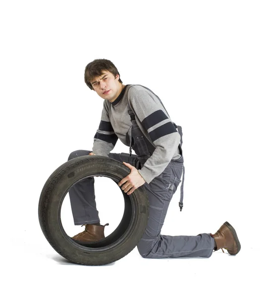 En ung brunetformann i grå arbeidsklær med svart hjul. . – stockfoto
