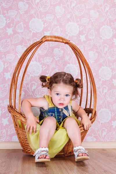 Girl sitting on a wicker basket — Stock Photo, Image