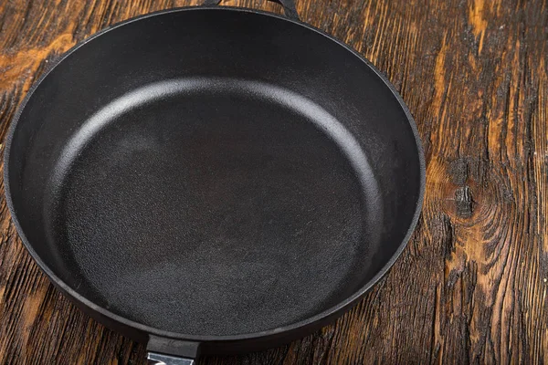 A cast-iron frying pan on a wooden background — Stock Photo, Image