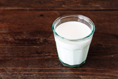 Tahta arka planda bir bardak süt.