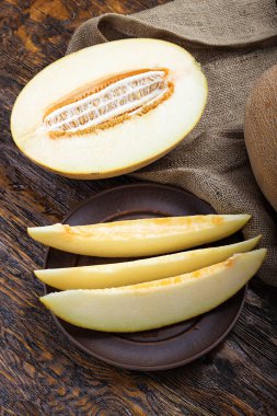 Kahverengi ahşap bir masa dilimler halinde kesip sulu olgunlaşmış kavun