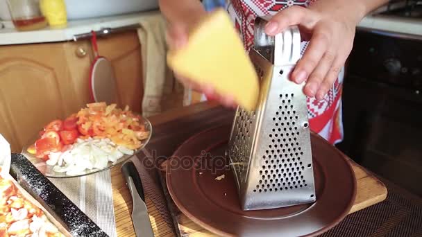 Дівчина натирає сир на кухні — стокове відео