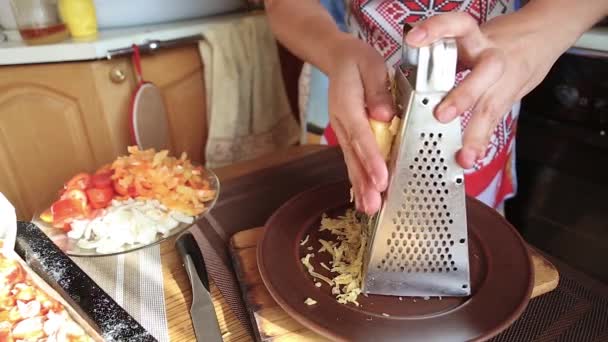 Дівчина натирає сир на кухні — стокове відео