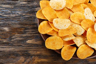 Eski mutfak masasında bir çanak çömlek tabak içinde gevrek patates cipsi