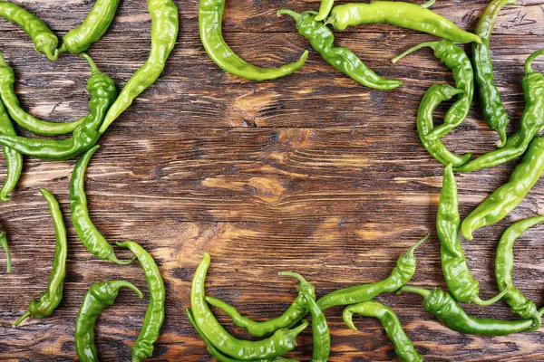 A lot of green chili peppers on a vintage wooden background. — Stock Photo, Image