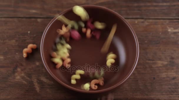 Varicoloured pasta is poured into a plate — Stock Video