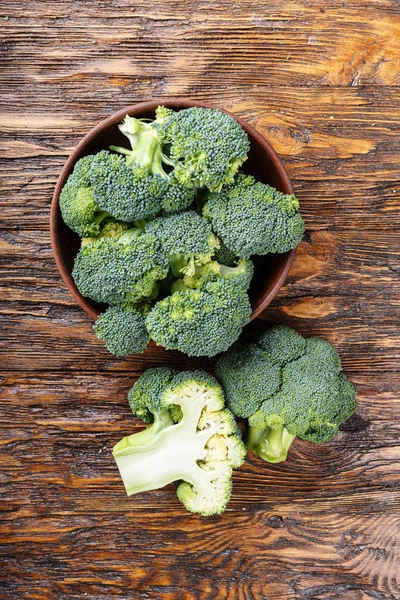 Brokoli di piring tanah liat di atas meja kayu, di samping seluruh kabin — Stok Foto