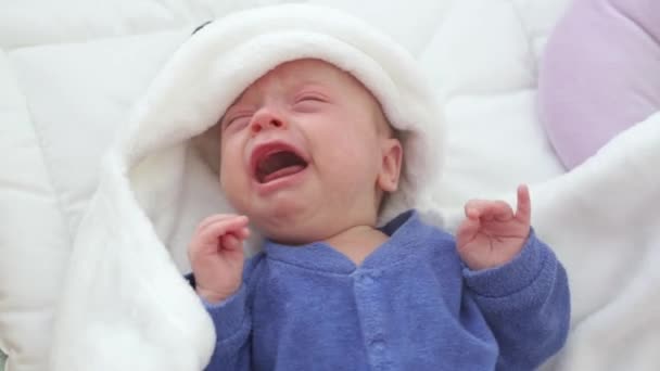 Newborn crying baby boy. New born child tired and hungry in bed under a blue knitted blanket. — Stock Video