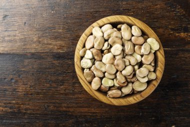 ahşap arka plan üzerinde bir tabak içinde pişmemiş kuru fasulye. Üstten Görünüm. 