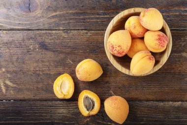 Masanın üzerindeki ahşap kasede lezzetli olgun kayısılar.