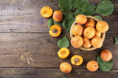 Masanın üzerindeki ahşap kasede lezzetli olgun kayısılar.