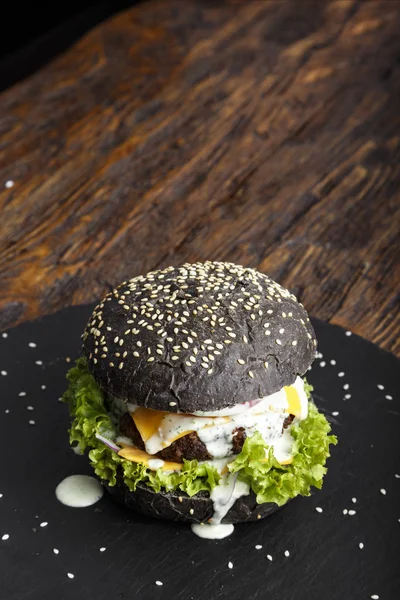 Černý burger na břidlicové desce — Stock fotografie