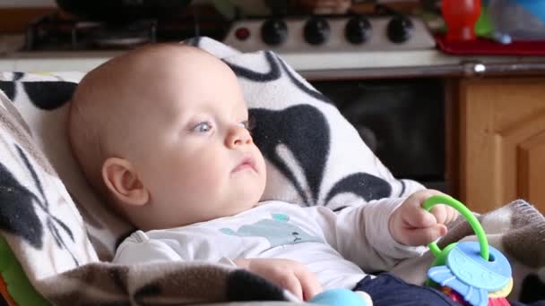 Bebê com um chocalho sentado em uma cadeira alta — Vídeo de Stock