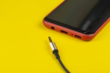 Kapalı çekim prizi ve sarı arka planda telefonu olan bir kablo.