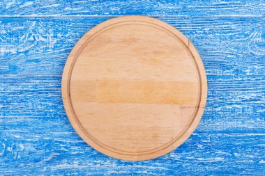 Mavi bir arka plan üzerinde yuvarlak kesme tahtası.