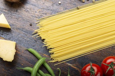 Ahşap arka planda sebzeli çiğ spagetti.