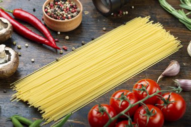 Ahşap arka planda sebzeli çiğ spagetti.