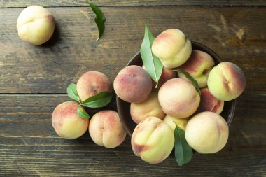Ripe peaches in  plate on wooden background.