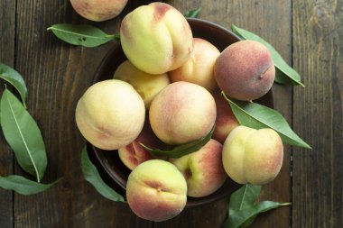 Ripe peaches in  plate on wooden background.