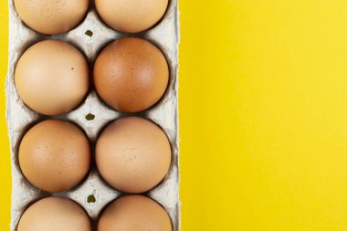 Sarı arka planda kahverengi yumurtalar.