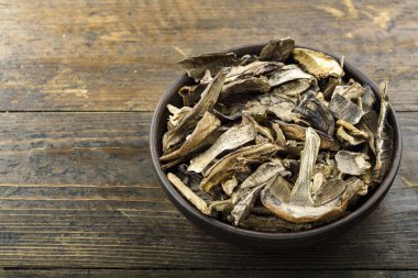 Kurutulmuş mantarlar eski ahşap bir arka planda, bir tabakta dilimlenmiş..