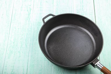 Fresh black cast-iron skillet on a wooden background. place for tex