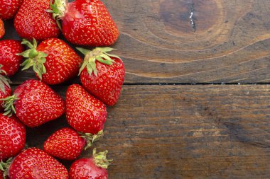 Olgun organik çilekler kahverengi ahşap bir arka planda sıralanmış. tex için yer