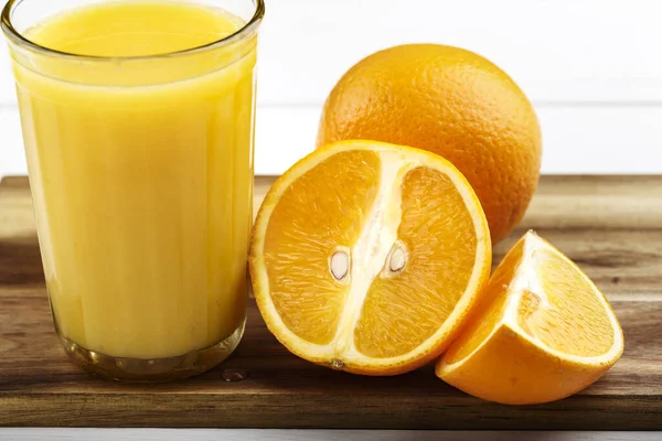 glass of juice and oranges on a wooden cutting board. vitamin drink for breakfast. source of vitamin C. place for text