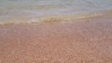kumlu sahilde şeffaf deniz dalgaları.