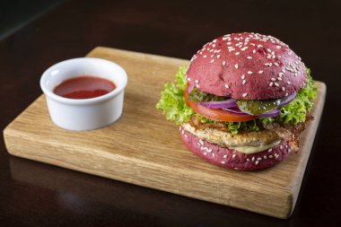 Pirzola ve tahta kesme tahtasındaki sebzeli kırmızı burger. metin için yer.