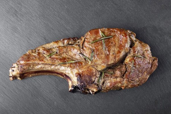 Steak on the bone. Tomahawk steak on a black background. View from above. Space for text.