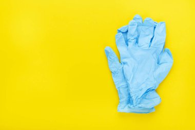 Sarı arka planda mavi tıbbi eldiven. Üst görünüm.