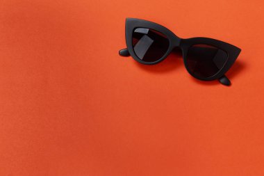 Turuncu arka planda modaya uygun güneş gözlükleri. Yaz konsepti, metin için yer.