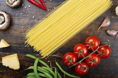 Ahşap arka planda sebzeli çiğ spagetti. Geleneksel İtalyan yemeği. İştah açıcı mutfak arka planı