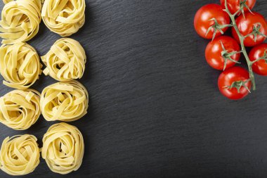 Kara tahtada çiğ tagliatelle makarnası. Yemek pişirme konsepti. Üst görünüm.