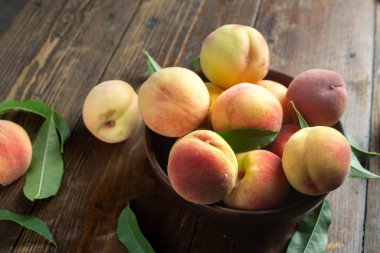 Tahta arka planda yaprakları olan olgun şeftali hasadı. tex için yer