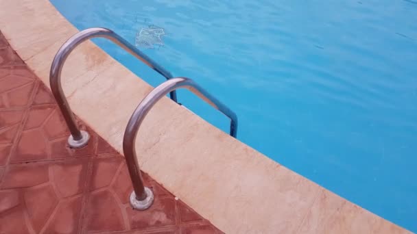 Kovový žebřík k bazénu. v bazénu je průzračná modrá voda. — Stock video