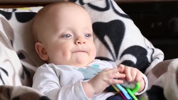 Bebê com um roedor de plástico está sentado em uma cadeira alta. — Vídeo de Stock