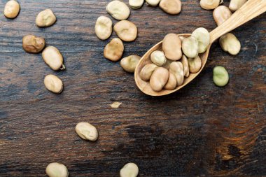 Tahta kaşıkta kuru fasulye ve masaya serpiştirilmiş. tex için yer