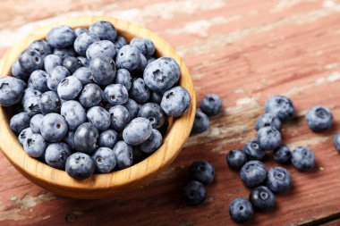 Ahşap bir tabakta organik yaban mersinleri ve ahşap bir zemine serpiştirilmiş bir masa. metin için yer