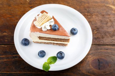 ahşap bir arka plan üzerinde bir tabakta kahve kreması ve yaban mersini ile kek dilim. tex için yer