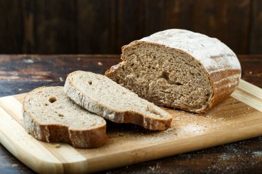 Kahverengi ahşap arka planda dilimlenmiş taze çavdar ekmeği. Basit bir kırsal grup