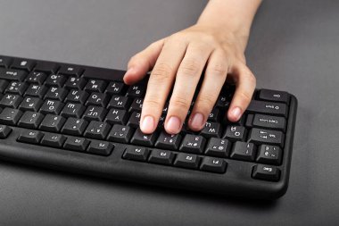 Kadın eli siyah bir bilgisayar klavyesinde. Kız bilgisayarda yazıyor.