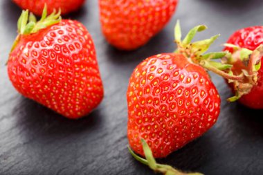 Siyah arka planda olgun taze çilekler. mesaj için yer. Arka planda böğürtlenler bulanık