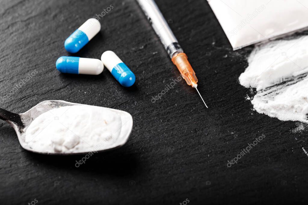 drug white powder sprinkled on a black table. next syringe. dangerous illegal business. place for tex